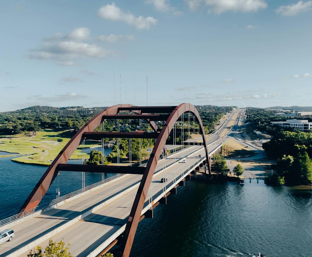A stunning aerial shot of Pennybacker Bridge over Lake Austin on a clear summer day