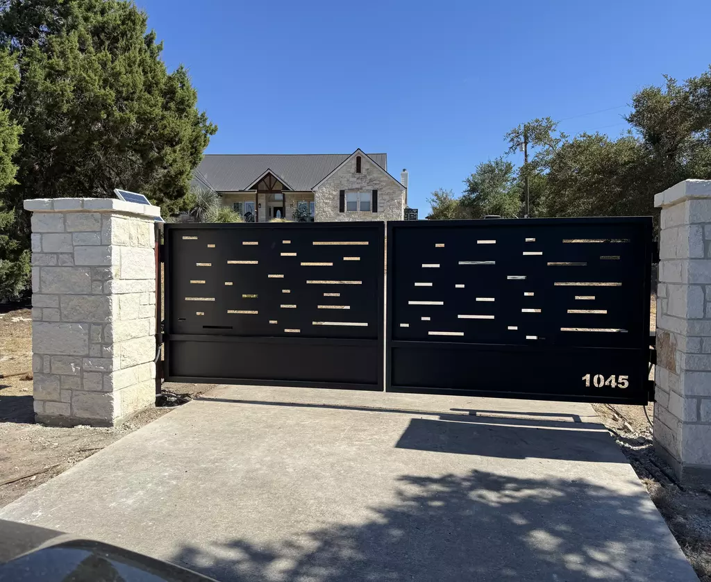 Modern black finish Flat Top Metal Swing Driveway Gate with privacy slits and stone pillars on either side